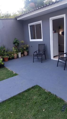 a patio with two chairs and plants in front of a house at Suíte completa na Região do Lago in Cascavel
