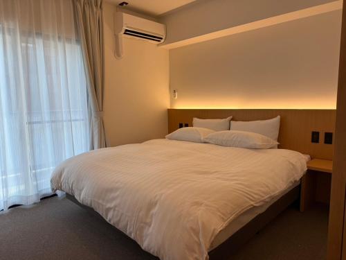 a bedroom with a large white bed with a window at レジデグローバル熊本 in Kumamoto