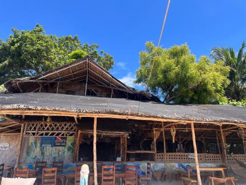 a building with tables and chairs in front of it at Bamboo Nest Beachfront in Puerto Princesa City