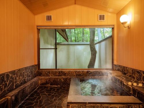 a jacuzzi tub in a room with a window at AZUMINO KOGEN Resort in Azumino