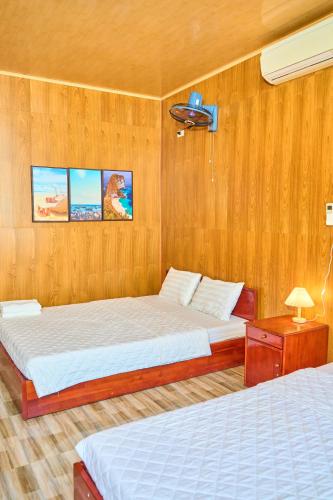 two beds in a bedroom with wooden walls at Bugalow Tiên Sa Cô Tô in Nam Cap