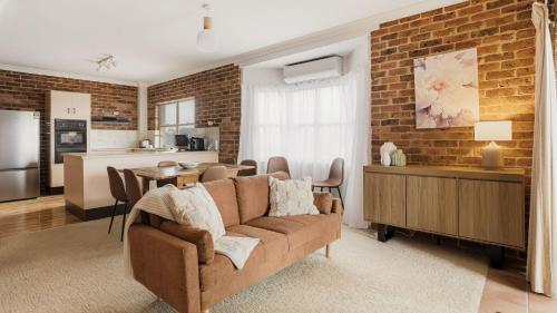 a living room with a couch and a brick wall at North Street Panorama in Urunga
