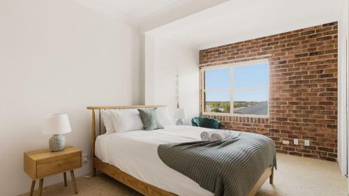 a bedroom with a bed and a brick wall at North Street Panorama in Urunga
