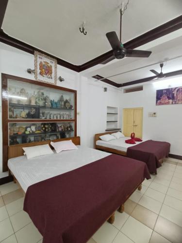 a bedroom with two beds and a ceiling fan at Adb's Kuzhlam Traditional Homestay & Rooms in Tiruchirappalli