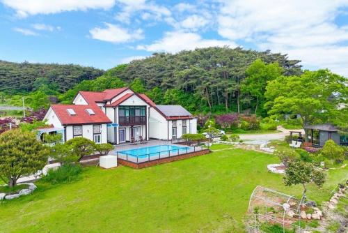 a house with a swimming pool in a yard at Anmyeondo Chingunae Pension in Taean