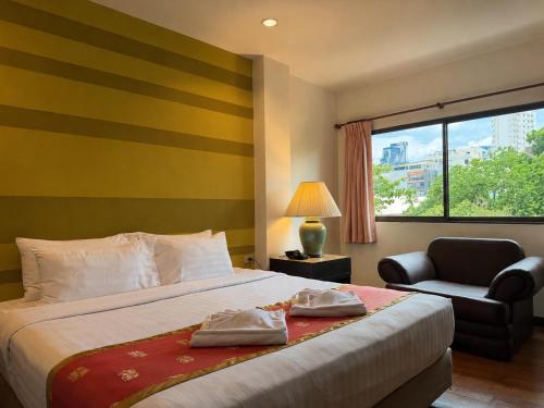 a bedroom with a bed and a chair and a window at Woraburi Sukhumvit Hotel in Bangkok