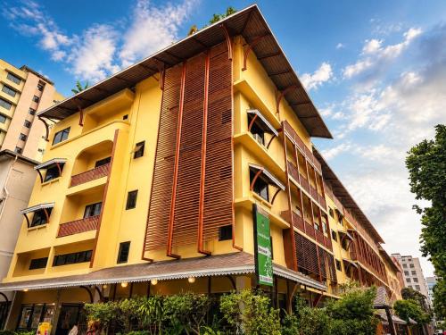 a yellow building with wooden shutters on it at Woraburi Sukhumvit Hotel in Bangkok