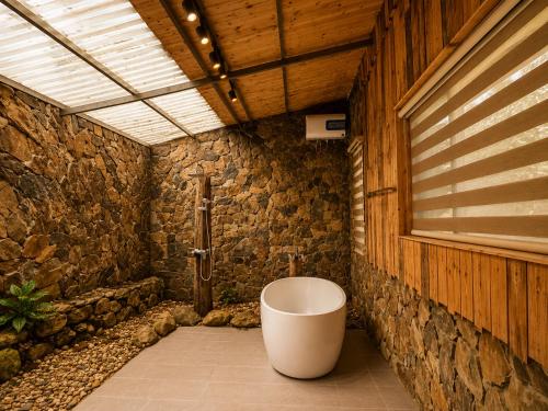 a bathroom with a bath tub in a stone wall at Zenna Lake Retreat in Tien Xuan