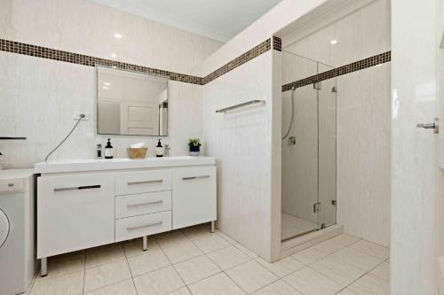a white bathroom with a shower and a sink at Sunkissed & Studio in Vincentia