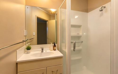 a bathroom with a sink and a shower with a mirror at Cube Lite Apartments in Hamilton