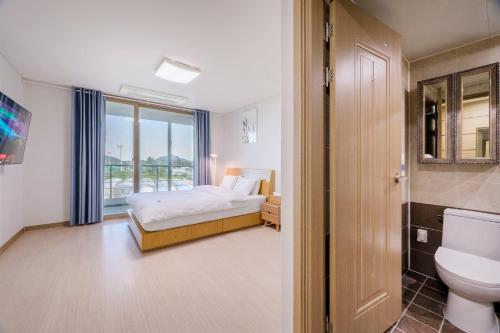 a bedroom with a bed and a toilet and a window at Dorami Pension in Seogwipo