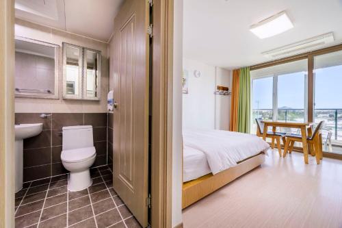a bathroom with a bed and a sink and a toilet at Dorami Pension in Seogwipo
