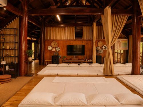 a large room with white beds and a television at Zenna Lake Retreat in Tien Xuan
