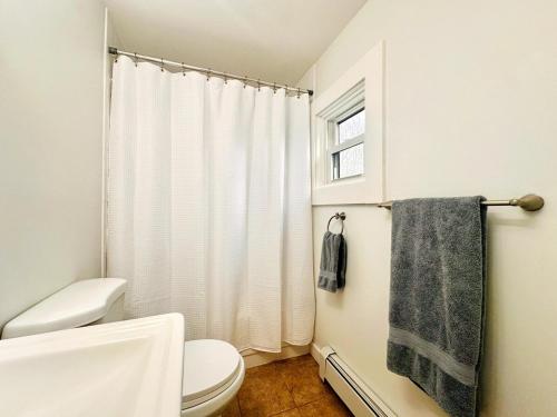 a bathroom with a toilet and a shower curtain at Shorebreak Cottage in North Kingstown