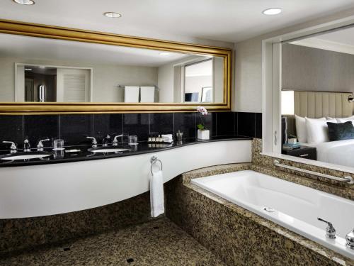 a bathroom with a tub and a large mirror at Fairmont Vancouver Airport In-Terminal Hotel in Richmond