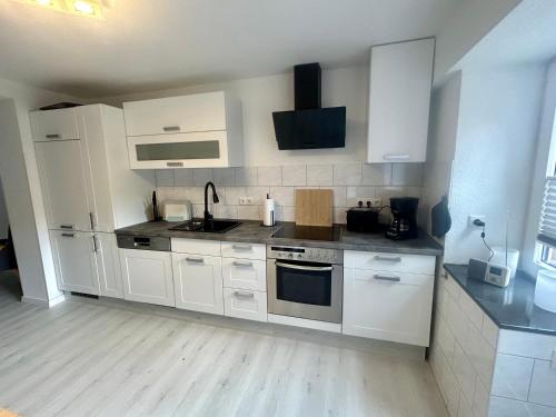 a kitchen with white cabinets and white appliances at Kastanienidyll in Grabowhöfe