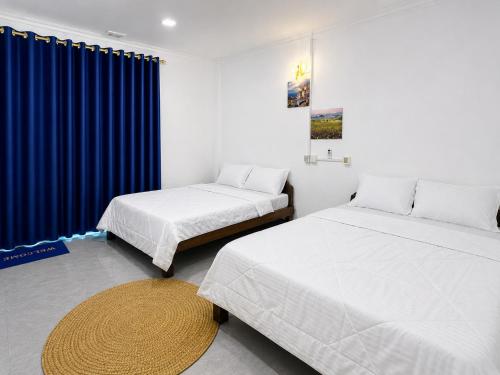 a bedroom with two beds and a blue curtain at David's Hostel & Restaurant in Kaôh Rŭng (3)