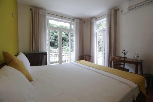 a bedroom with a large white bed and windows at Green Royal Villa in Kandy