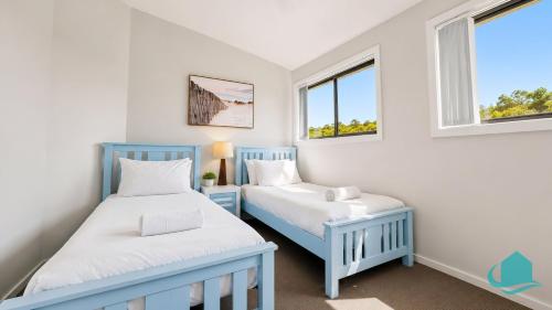 two beds in a small room with windows at Beachside Beauty in Caves Beach
