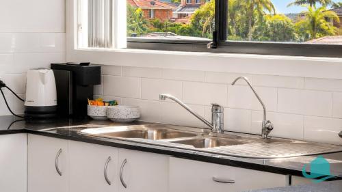 a kitchen counter with a sink and a window at Beachside Beauty in Caves Beach