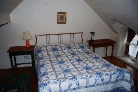 una camera con un letto con una coperta blu e bianca di Cul Cottage a Valentia Island