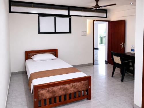 a bedroom with a bed and a table and a desk at Serene Enclave in Nedumbassery