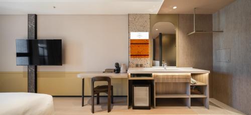 a bathroom with a sink and a desk with a tv at Boutech hotel Banqiao Yellowstone in Taipei