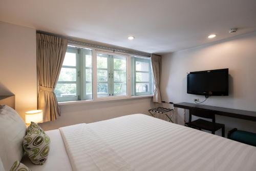 a bedroom with a bed and a flat screen tv at 24 Inn at BTS Phrom Phong in Bangkok