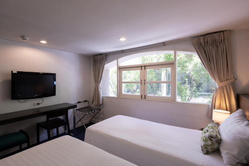 a hotel room with two beds and a window at 24 Inn at BTS Phrom Phong in Bangkok