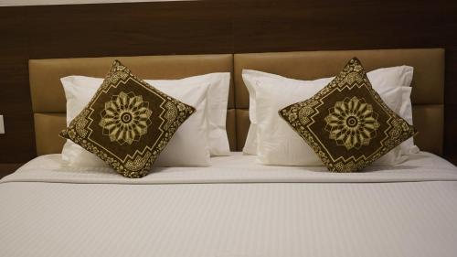 a bed with two pillows on top of it at The King's Hotel in Tuticorin