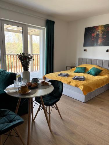 a bedroom with a bed and a table and chairs at Flauta Apartamenty in Augustów