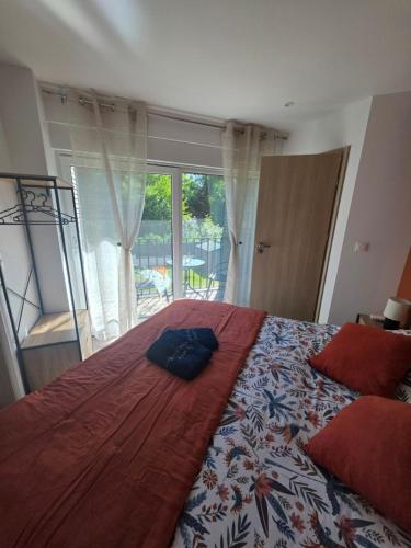 a bedroom with a large bed with a red blanket at Le Petit L Orée des Bois in Blainville-sur-lʼEau