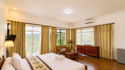 a bedroom with a bed and a couch and windows at Pondok Senaru Cottages in Senaru