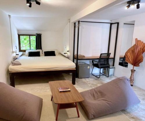 a bedroom with a bed and a couch and a table at MoovInn Garden Guesthouse in Ko Tao