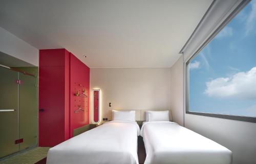 two white beds in a room with a window at Go Hotel Nakhon Sawan in Ban Pak Nam Pho