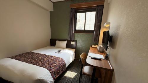 a small hotel room with a bed and a desk at Ueno Touganeya Hotel in Tokyo