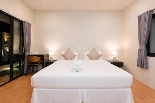 a bedroom with a large white bed with slippers on it at Ranong Adventure Resort & Park in Ranong