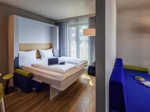 a bedroom with a bed with a laptop on it at Adagio Access Stuttgart Airport Messe in Leinfelden-Echterdingen