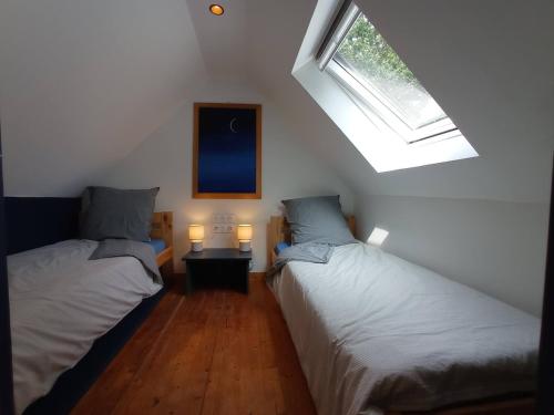 two beds in a room with a window and two lamps at Nice cottage in Brittany in Plouigneau