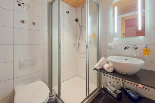 a bathroom with a shower and a sink and a toilet at Hotel Meielisalp in Leissigen