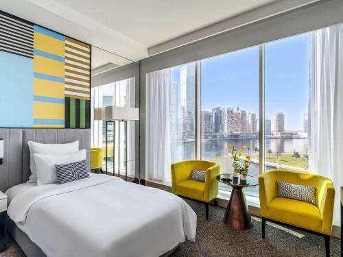 a hotel room with a bed and two chairs at Pullman Dubai Downtown in Dubai