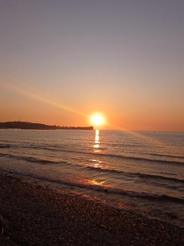 a sunset over the water on a beach at Dolphin Apt & Studios -Near the Beach in Roda