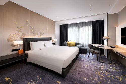 a hotel room with a large white bed and a desk at Hotel Nikko Kaohsiung in Kaohsiung