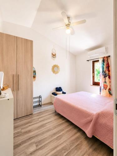 a bedroom with a pink bed and a ceiling fan at SweetHouse Pula in Porto Columbu - Perdʼe Sali