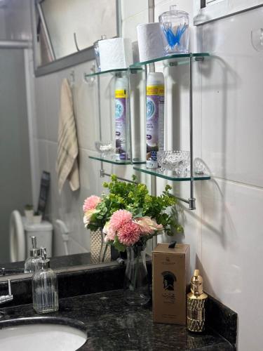 a bathroom with a sink and a counter with flowers at Rondon Sunset Belas Artes - 3Q - 3 salas - Sacada in Uberlândia