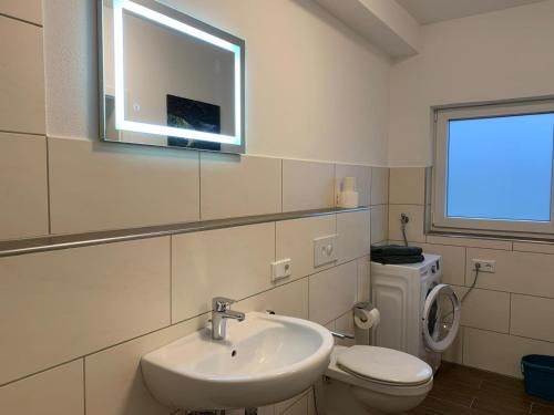 a bathroom with a sink and a toilet and a window at Schöne Ferienwohnung bei Lennestadt in Kirchhundem