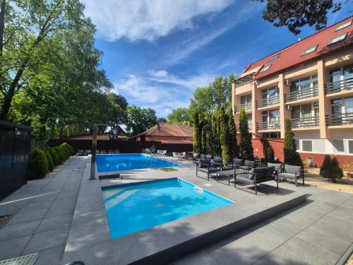 a swimming pool with chairs and a building at Hotel Korona in Siófok