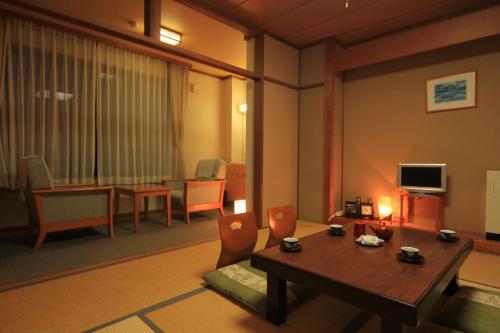 a living room with a table and chairs and a television at Eshin no Sato Yasuragisou in Joetsu