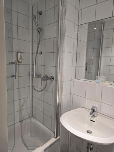 ein weißes Badezimmer mit Dusche und Waschbecken in der Unterkunft Hotel Boulevard in Köln