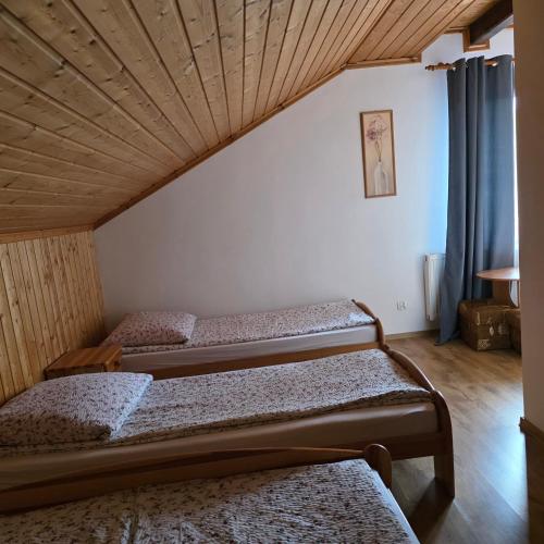 three beds in a room with a ceiling at Pod Smerekiem in Wetlina